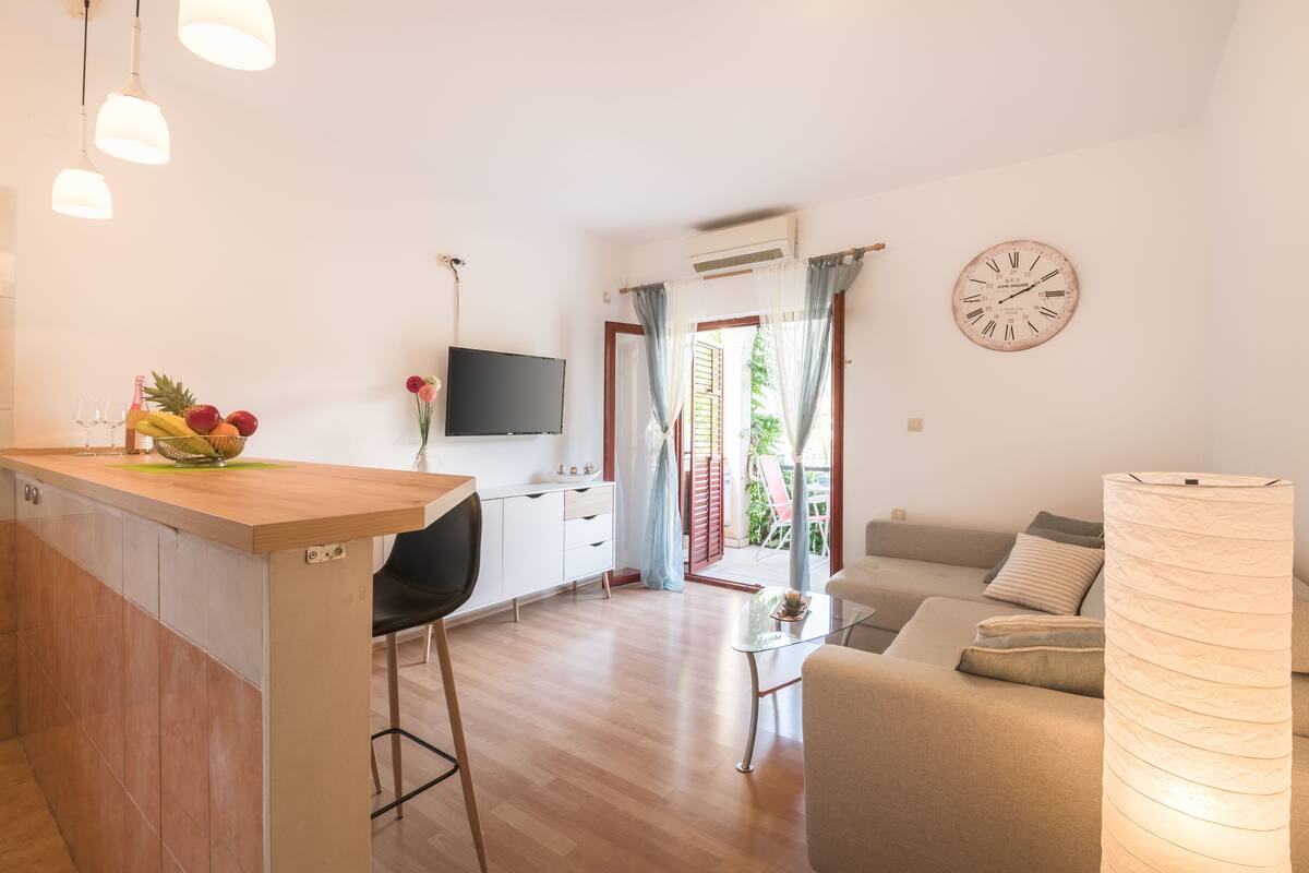 Eine moderne Küche mit Holzarbeitsplatte, ein Essbereich mit Glastisch und ein Wohnzimmer mit Sofa und Lampe.