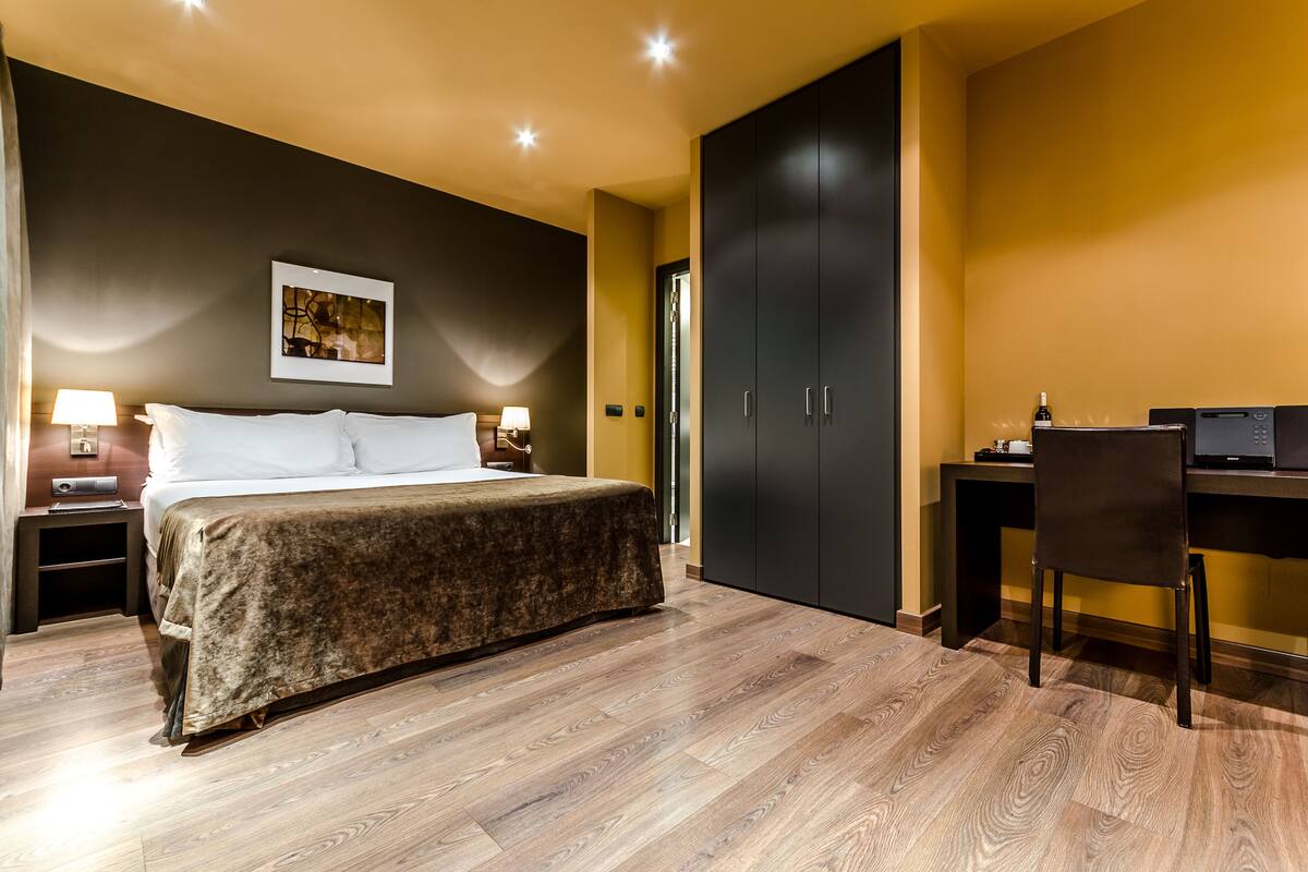 Un dormitorio con cama, mesitas de noche, un escritorio y una silla.