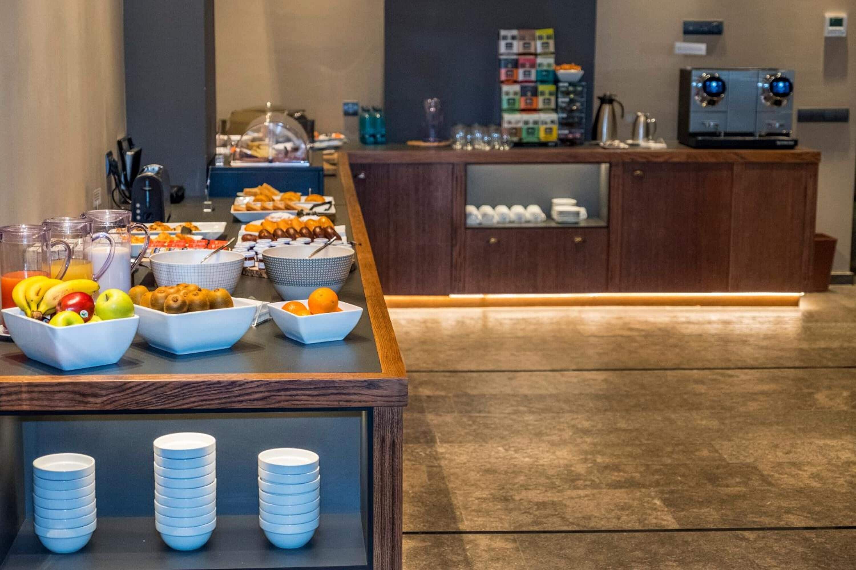 A breakfast buffet with various fruits, pastries, and beverages.