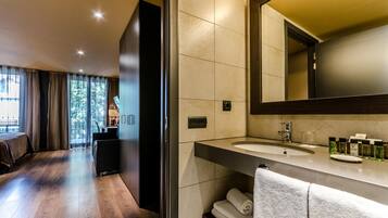 Un baño de hotel moderno con un espejo grande, dos lavamanos y una zona de tocador.