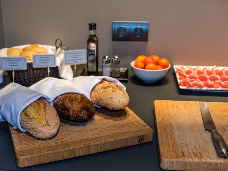 Una mesa de buffet con pan, tomates y un cuchillo sobre una tabla de cortar.