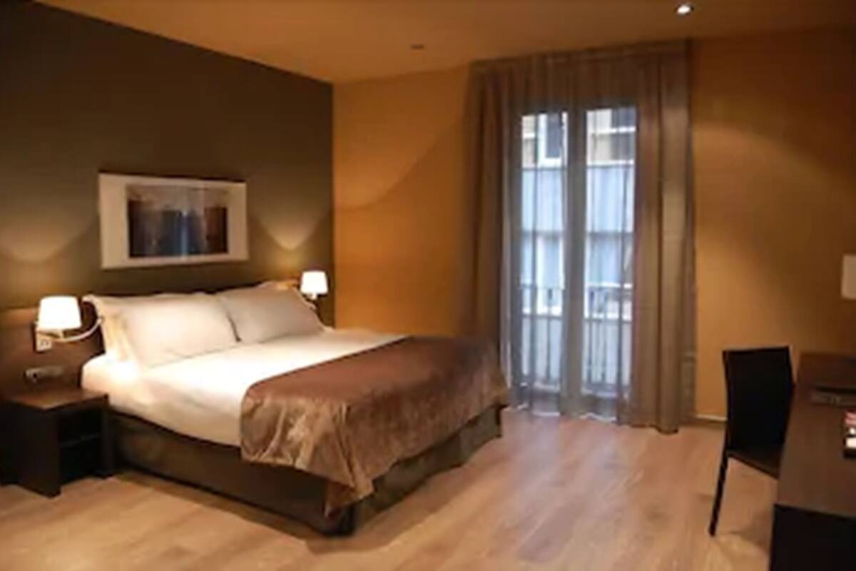 Un dormitorio con una cama, dos mesitas de noche, un escritorio y una silla.