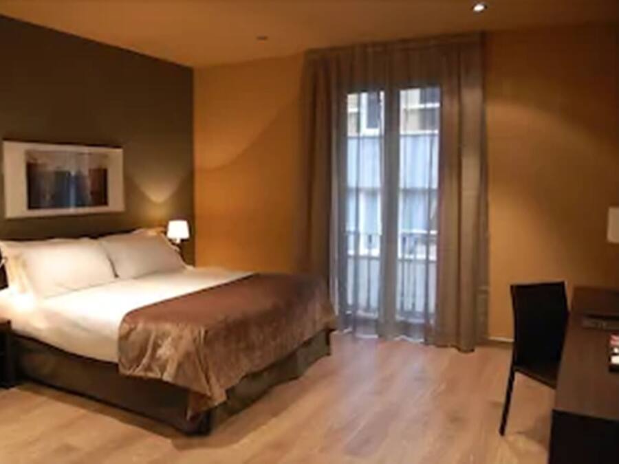 A bedroom with a bed, two bedside tables, a desk, and a chair.