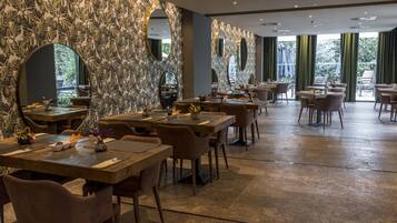 Un restaurante con paredes de diseño marmolizado, espejos redondos y diferentes tipos de asientos.