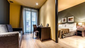 Una habitación de hotel con sofá, escritorio, cama y mesita de noche.