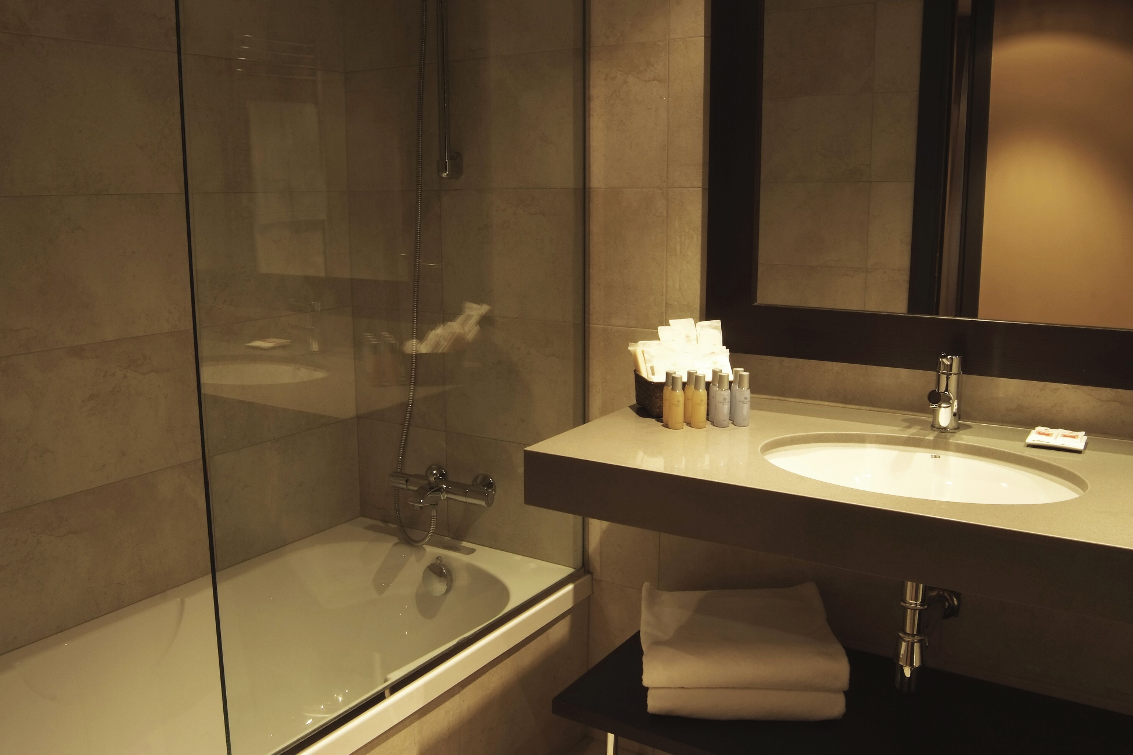 Un baño moderno con ducha envuelta en vidrio, una bañera, un tocador con lavabo y un espejo.