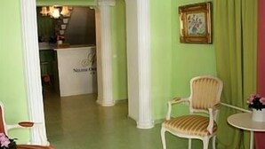A room with a white chair, a small round table, and a framed picture on the wall. - Nelisse One Hotel Bucharest (Bucharest)