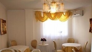 A dining area with round tables and chairs, a chandelier, and a window with curtains. - Nelisse One Hotel Bucharest (Bucharest)
