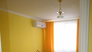 A small, brightly colored room with a bed, a desk, a television, and an air conditioning unit. - Nelisse One Hotel Bucharest (Bucharest)