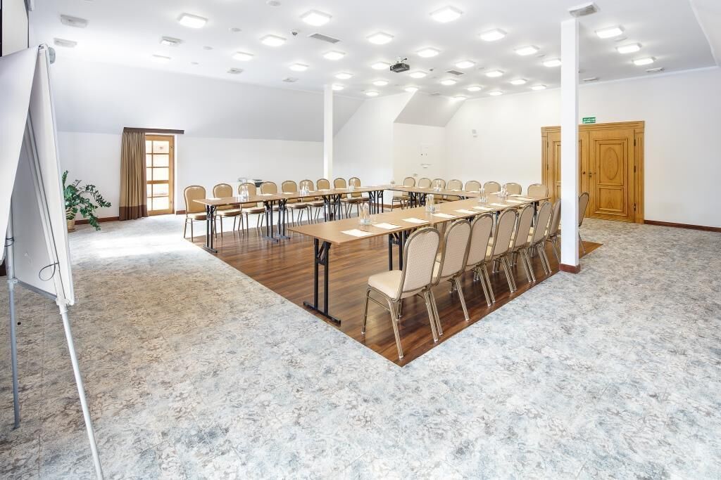 Una sala de conferencias con una larga mesa y sillas, paredes blancas y suelo de madera.