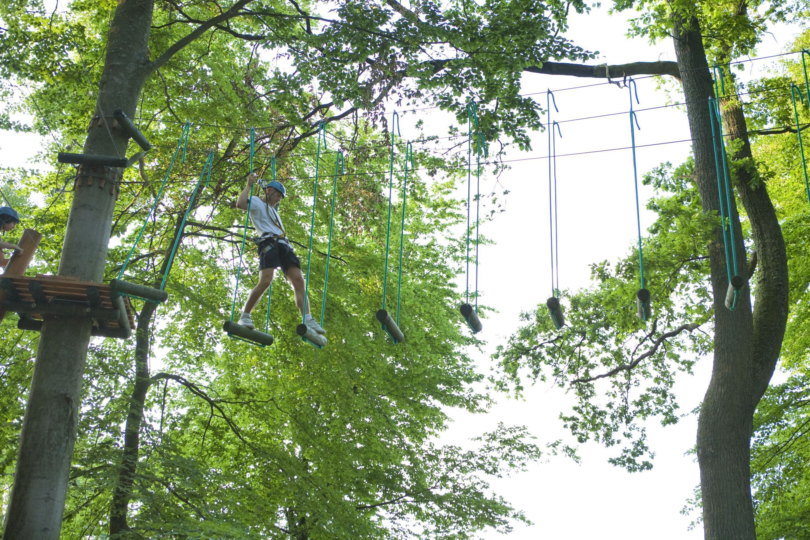 A person navigating an outdoor obstacle course in a wooded area.