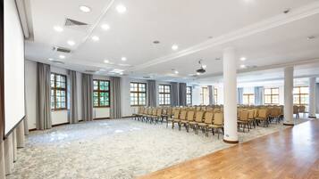 A large conference room with rows of chairs, a long table, and large windows.
