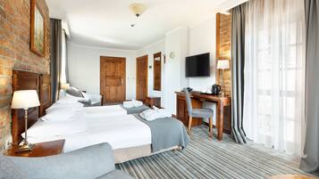 Ett hotellrum med en stor säng, ett skrivbord, en stol, en tv och en vägg av tegelsten.