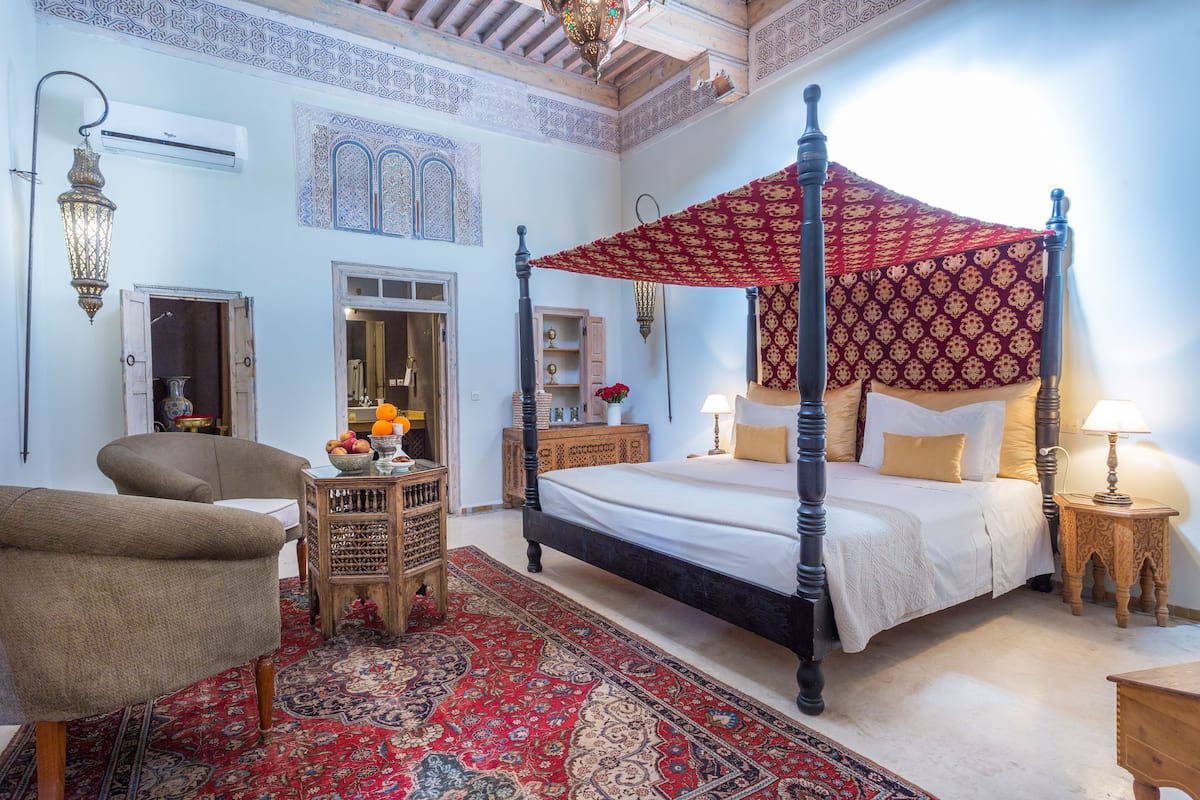 Um quarto tradicional com uma cama de dossel, um teto de cortinas vermelho estampado e piso de madeira.