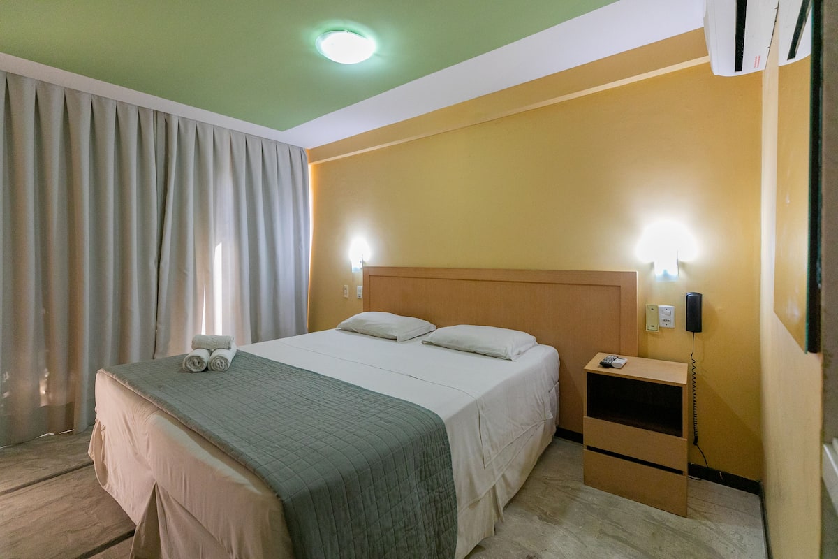 A hotel room with a bed, bedside table, and a nightstand.