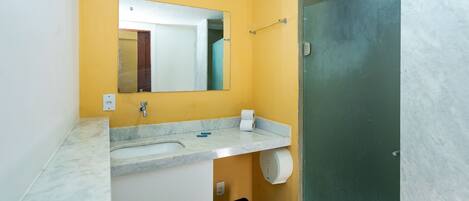 Un baño con una pared amarilla, un lavamanos blanco, un espejo y una puerta.