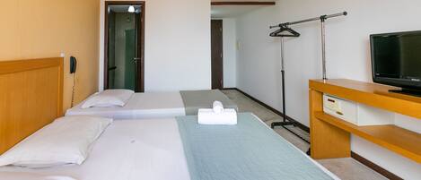 A hotel room with two beds, a TV, a desk, and a walk-in closet.