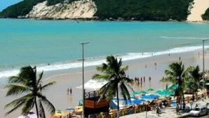 A beach with clear turquoise water, palm trees, and a sandy shore. - Safari Natal Beach Hotel (Natal)