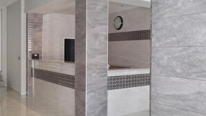 A hallway with a reception desk, a clock, and patterned tiles. - Euro Club Hotel (St. Paul's Bay)