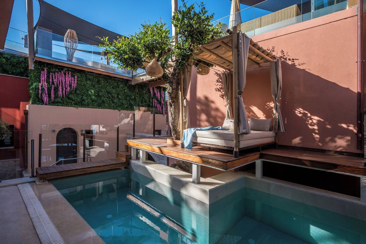 A modern outdoor pool area with a wooden deck, a lounge chair, and a pergola.