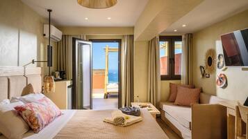Une chambre d’hôtel avec un lit, un canapé, un bureau et une vue sur la mer.