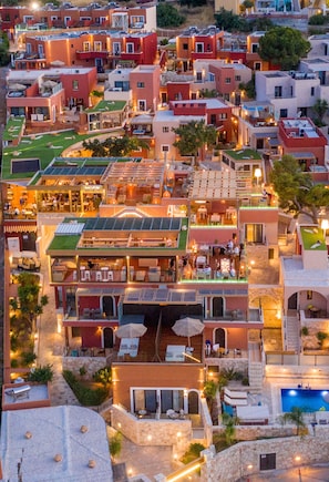 A multi-story hotel with outdoor seating areas, a swimming pool, and a rooftop terrace.