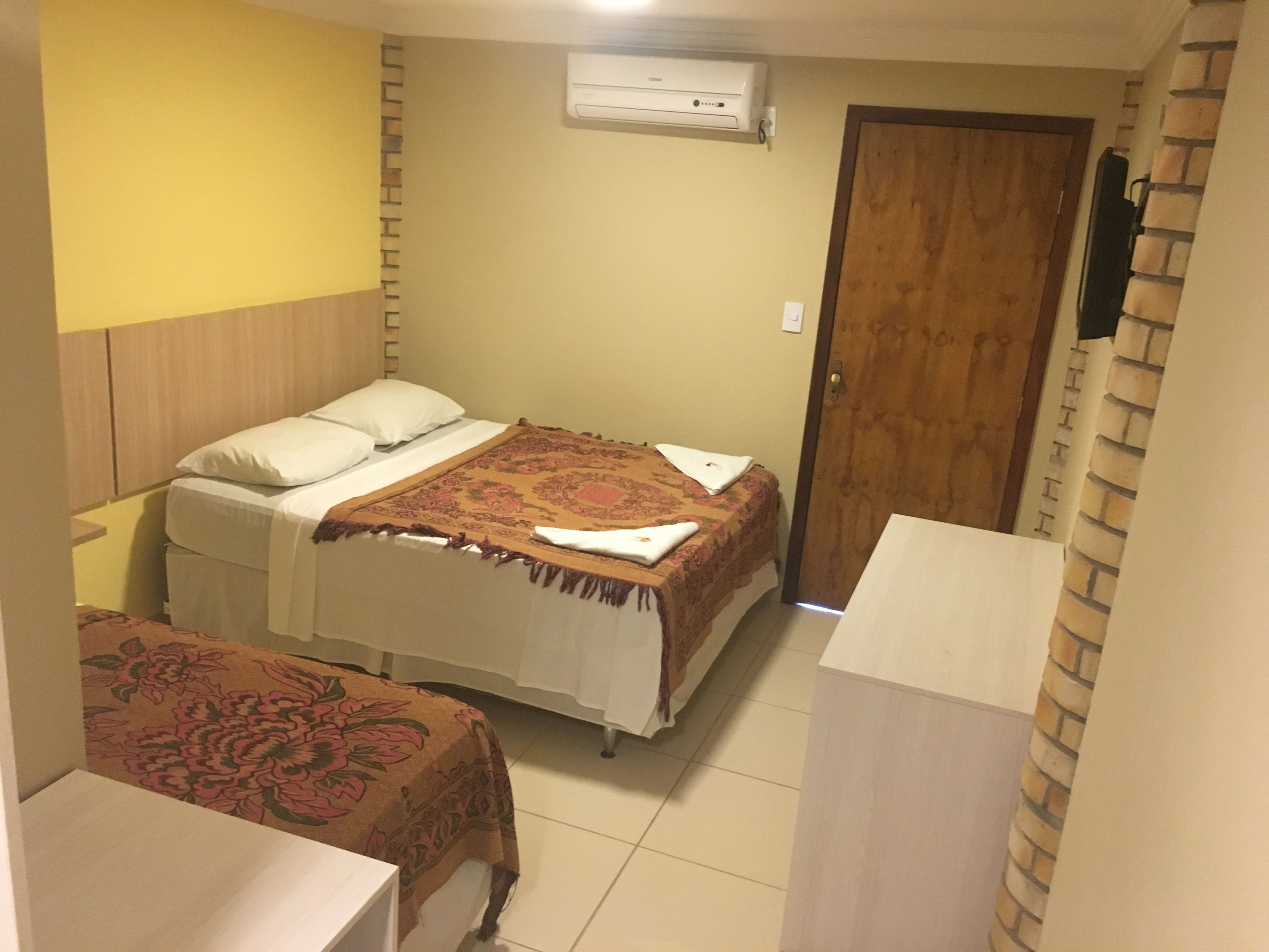 Quarto pequeno e compacto com cama, mesa de cabeceira e guarda-roupa.