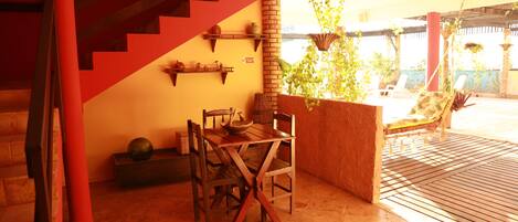 Un área de comedor con mesa y sillas, una escalera y vistas al exterior.