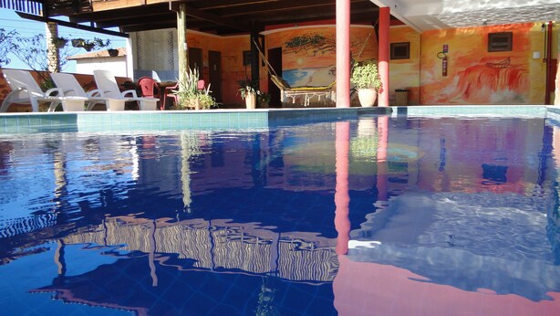 En swimmingpool med klart vand der spejler omgivelserne. Der er liggestole og plantekasser rundt om poolområdet.