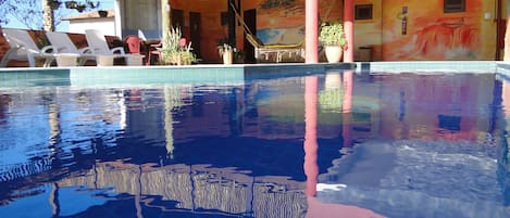 Una piscina al aire libre, sillones reclinables de piscina