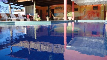 Una piscina al aire libre, sillones reclinables de piscina