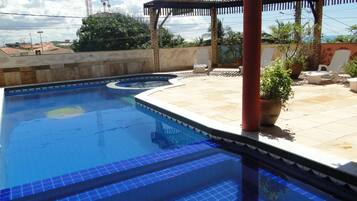 Una piscina al aire libre, sillones reclinables de piscina