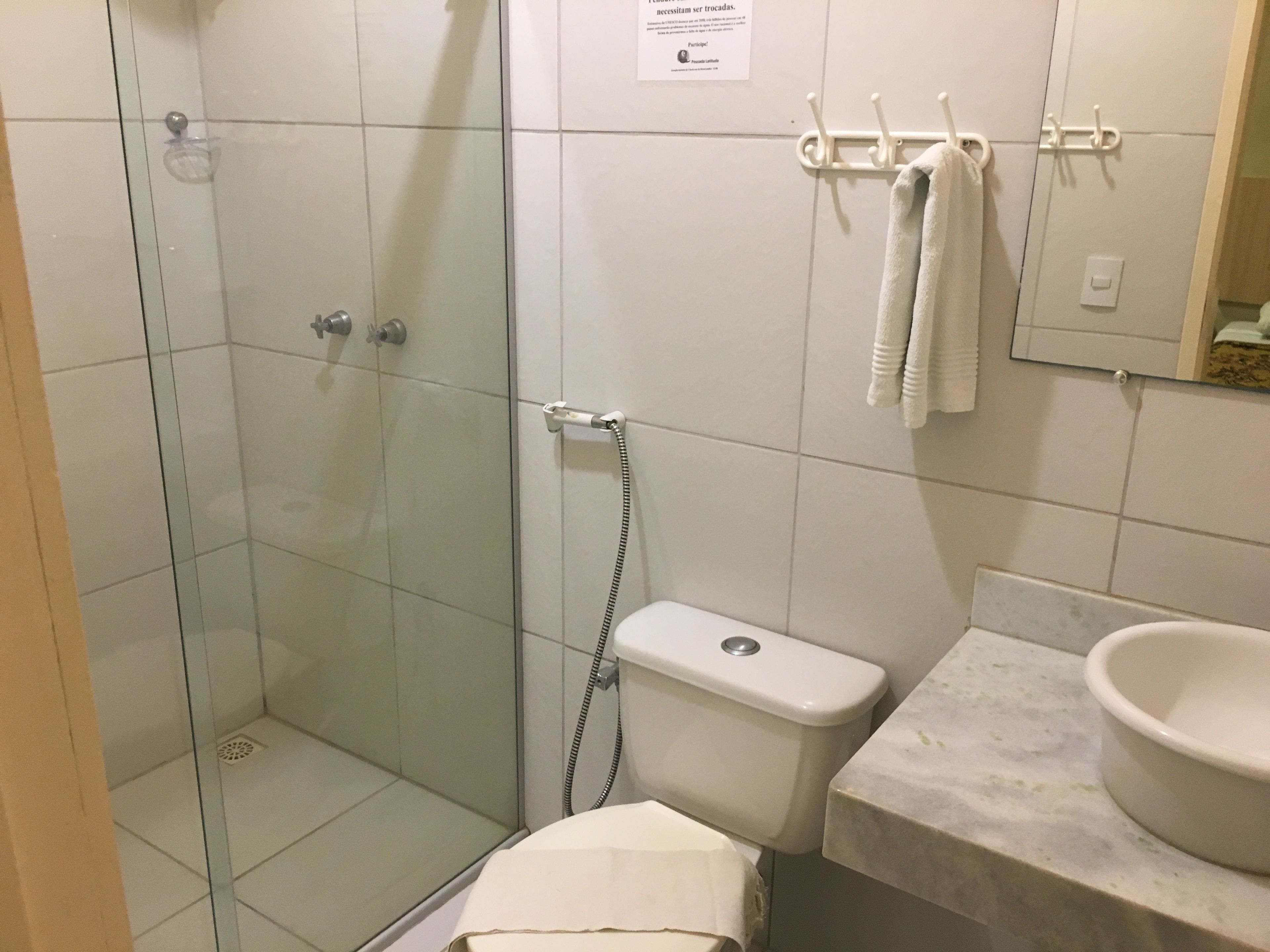 A bathroom with a glass-enclosed shower, a toilet, a sink, and a towel rack.