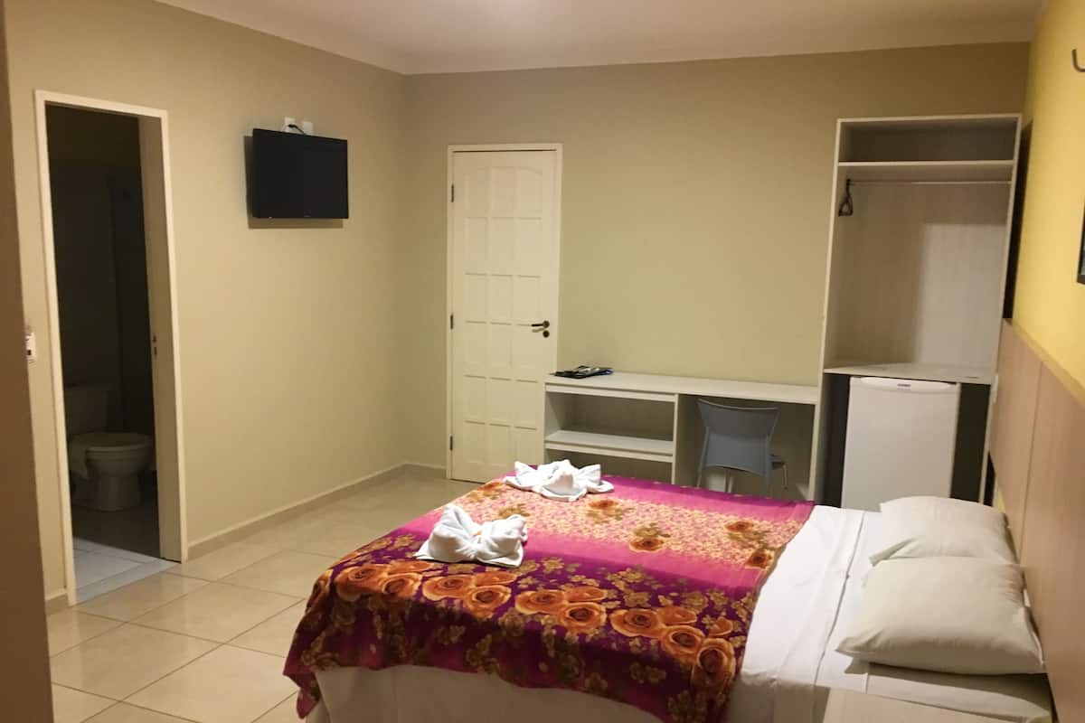 A bedroom with a bed, a desk, and a wardrobe.
