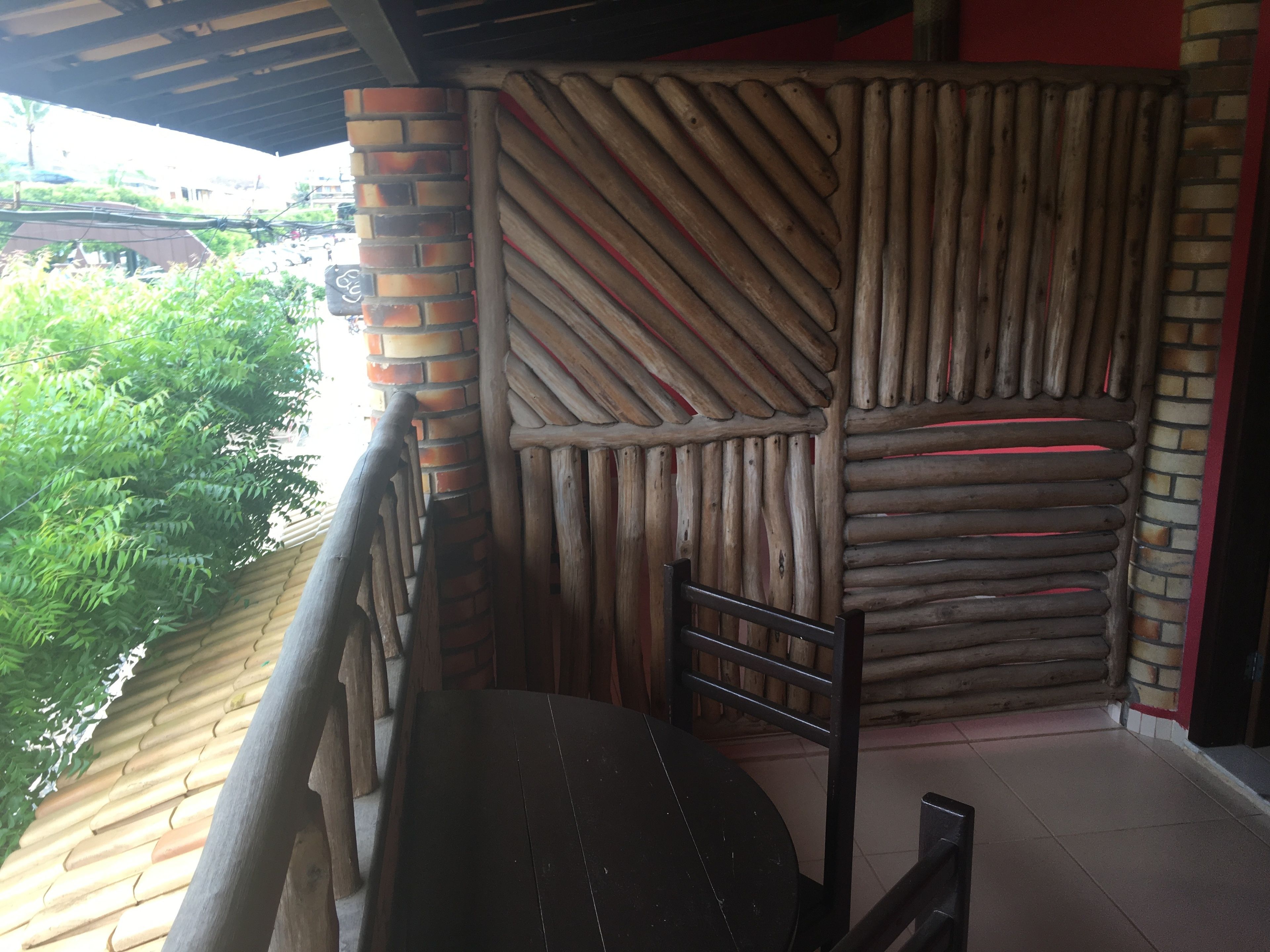 A wooden partition with a brick column, a wooden bench, and a tiled floor.