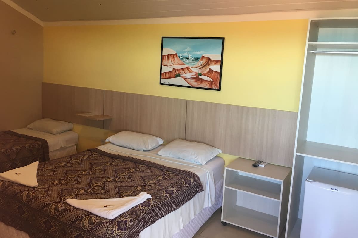 A hotel room with two beds, a painting on the wall, and a minibar.