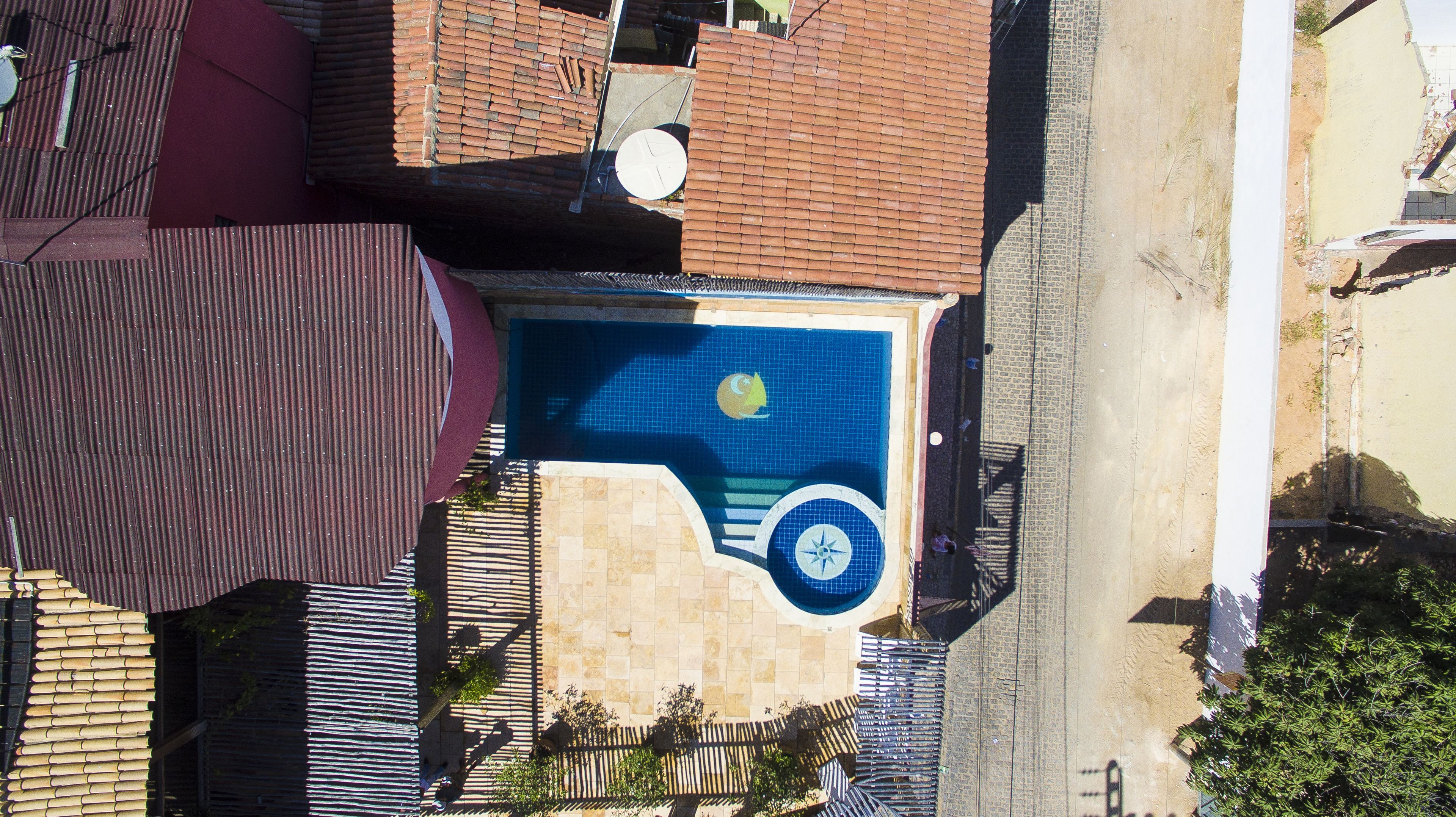 Vue aérienne d’un bâtiment doté d’une piscine, d’un toit rouge et d’une terrasse carrelée.