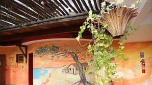 A mural of a tree on a wall, a fire extinguisher, and a wooden ceiling structure. - Pousada Latitude (Aracati)