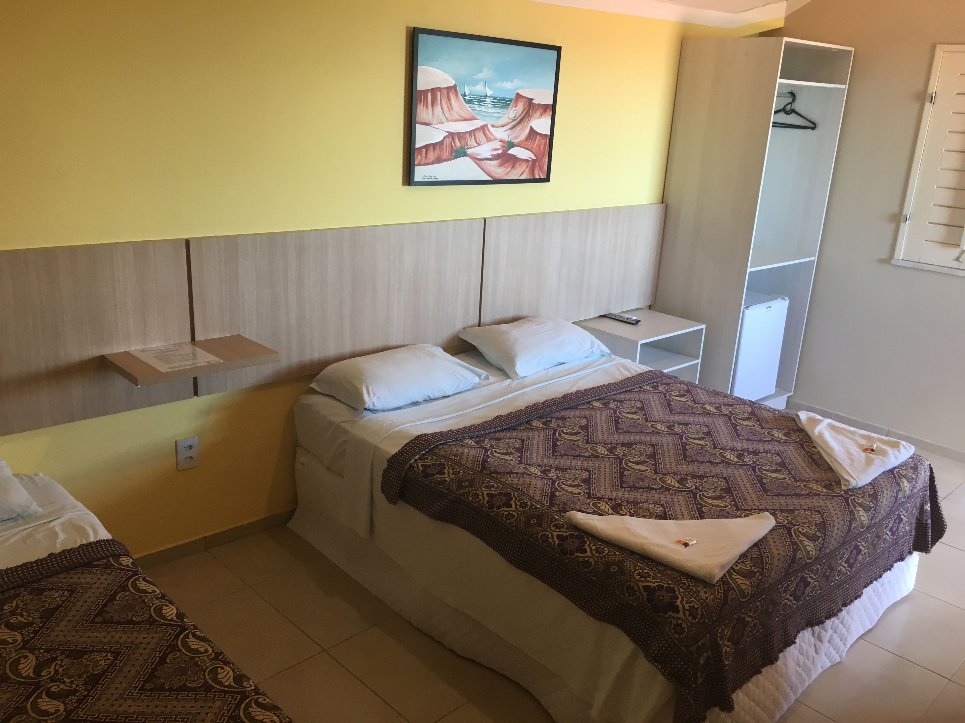 Une chambre à coucher comprenant un lit, des tables de chevet, une œuvre d’art suspendue et une armoire.