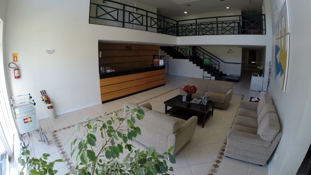Eine geräumige Lobby mit einer Rezeption, Sofas, einer Treppe und Blick auf die oberen Stockwerke.