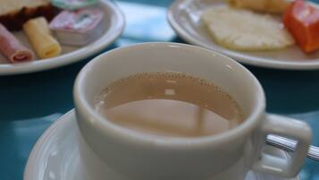 Uma chávena de café branco sobre um pires com asa, colocada sobre uma mesa.