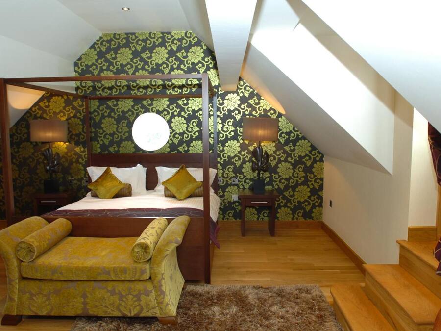 Une chambre à coucher avec un lit à baldaquin, un canapé, deux tables de chevet et un escalier.