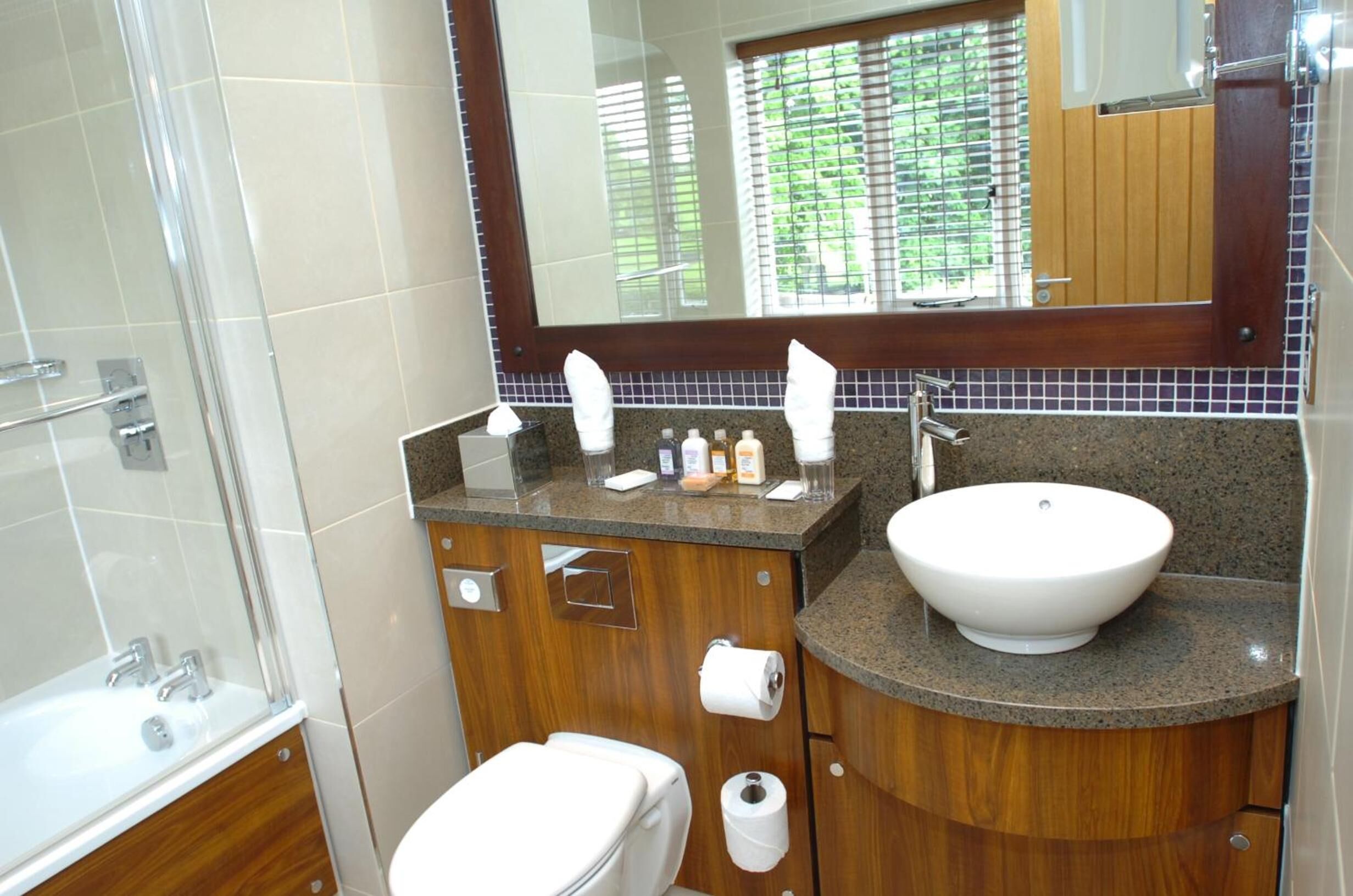 A bathroom with a white sink, wooden vanity, and a large mirror.