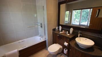 Een moderne badkamer met een bad, toilet en wastafel.