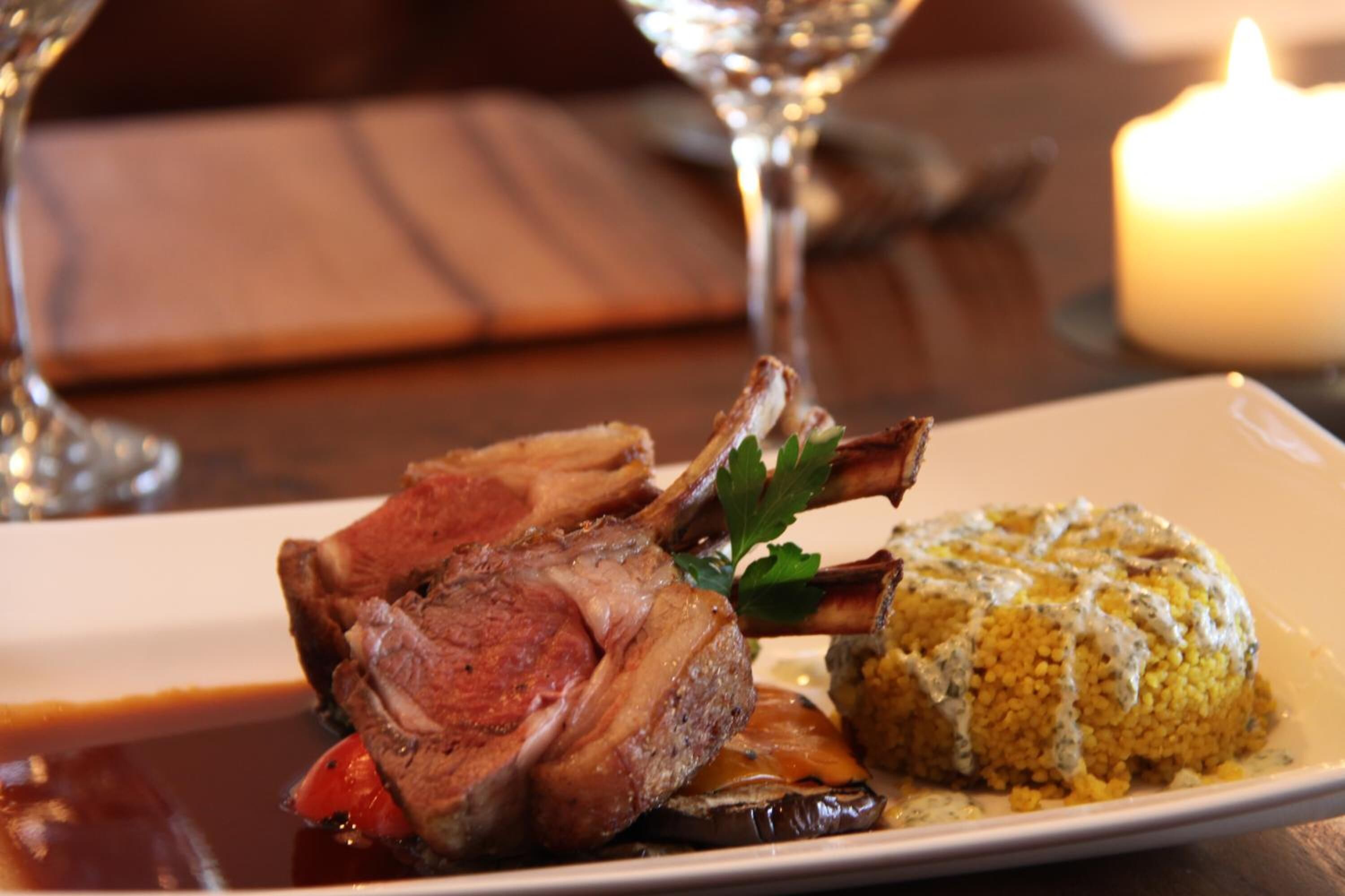 A plate with lamb chops, a yellow risotto, and a garnish of parsley.