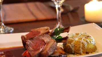 A plate with lamb chops, a yellow risotto, and a garnish of parsley.