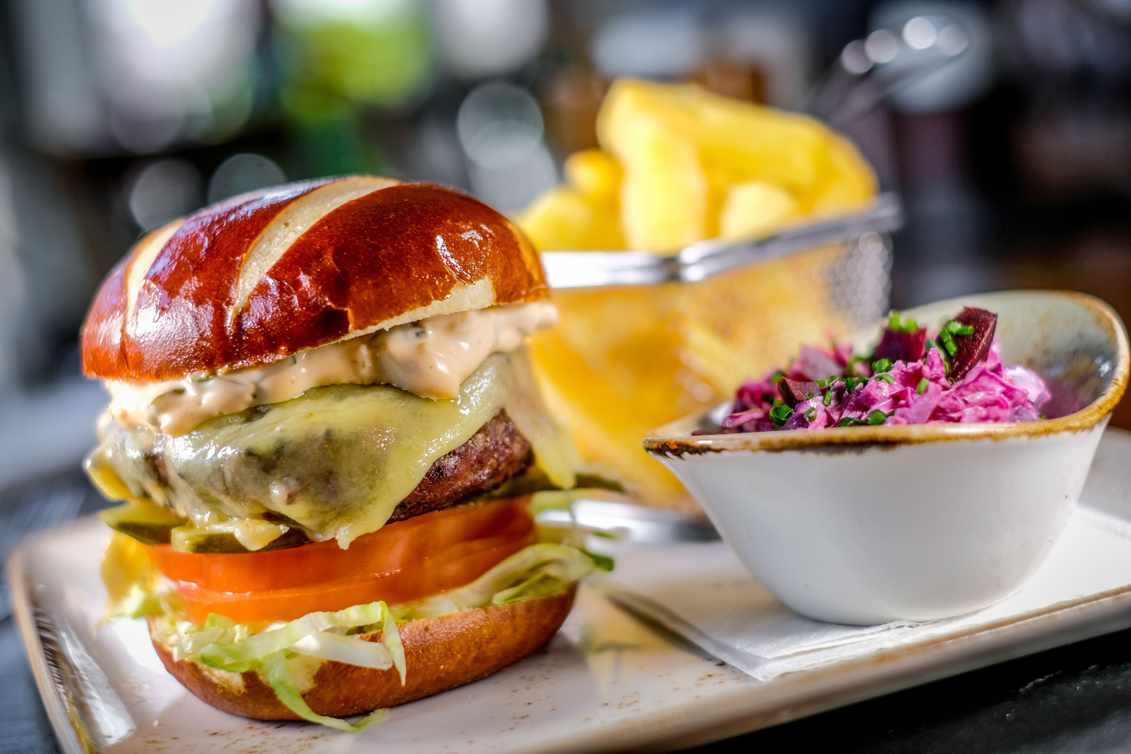A burger with a side of fries and a bowl of coleslaw.