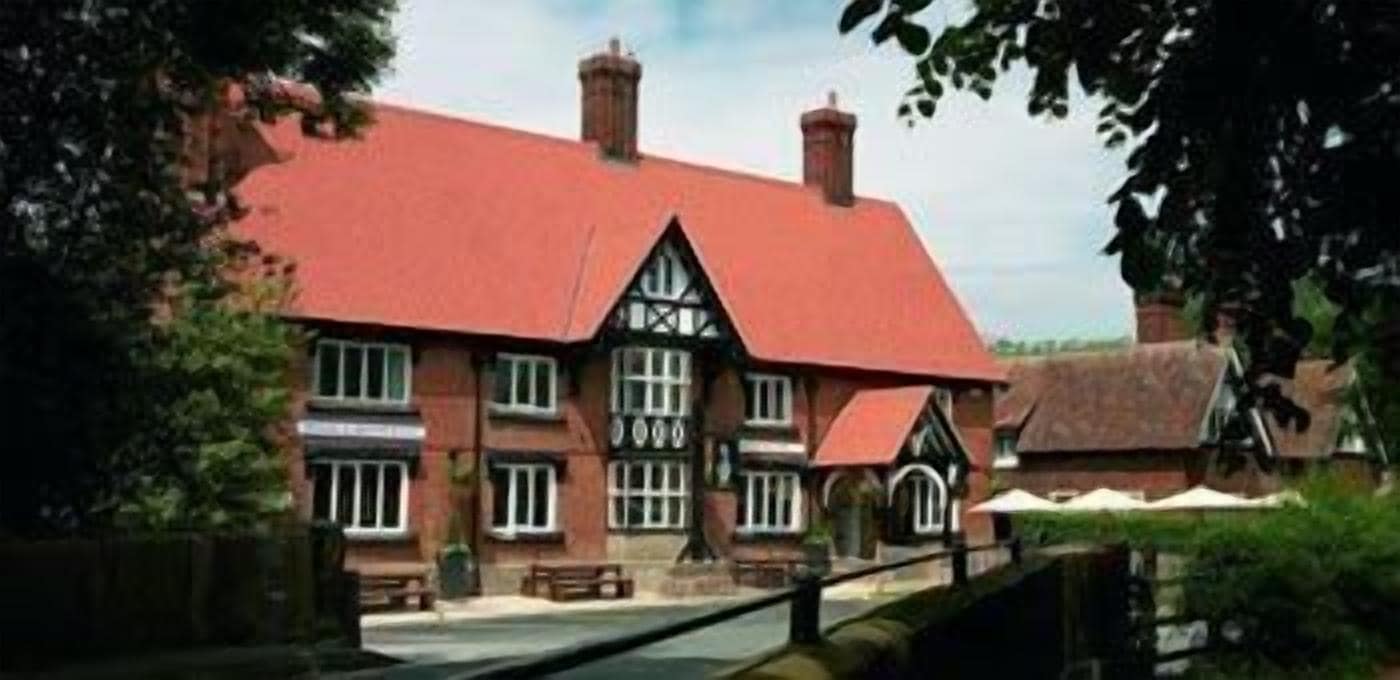 A traditional building with a red roof, multiple chimneys, and a brick facade.