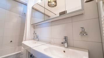 A modern bathroom with two sinks, a shower, and a mirror above the sinks.