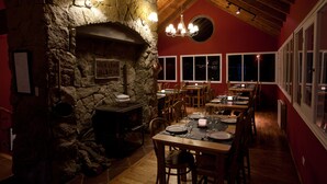 Un restaurante con chimenea de piedra, mesas y sillas de madera.